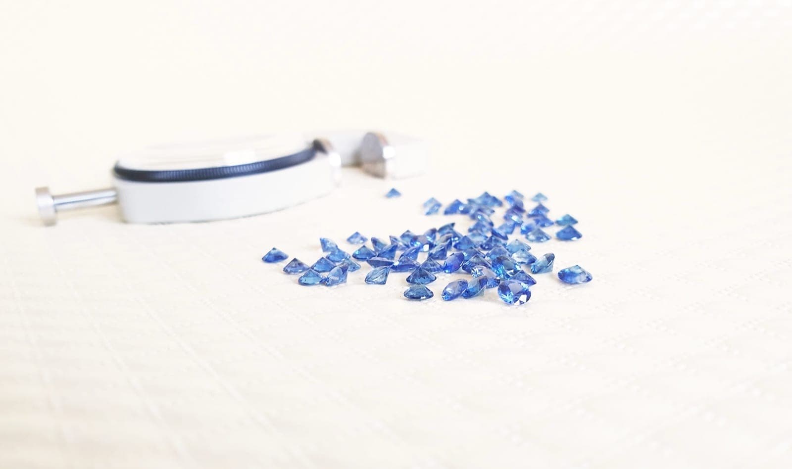 Blue sapphires arranged in a row showing the four saturation levels from vivid to weak, under D65 daylight lighting