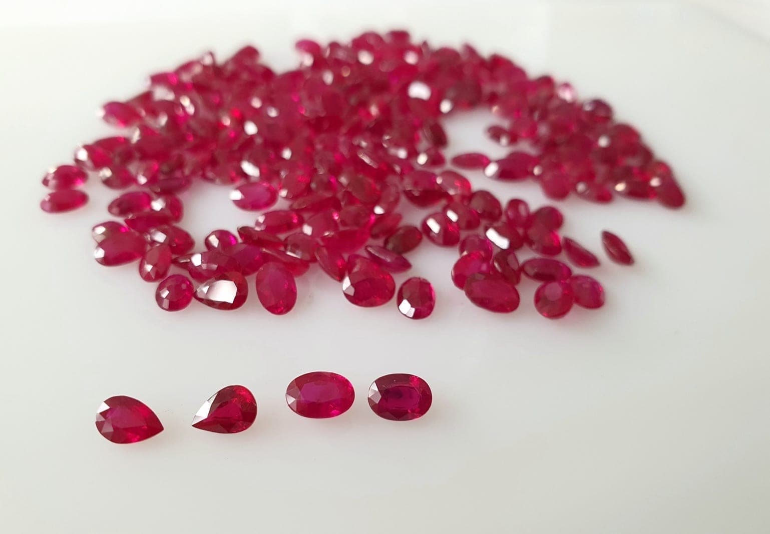 Dealer reviewing GRS and AIGS laboratory origin certificates for Burmese and Mozambique rubies at a Bangkok trading desk