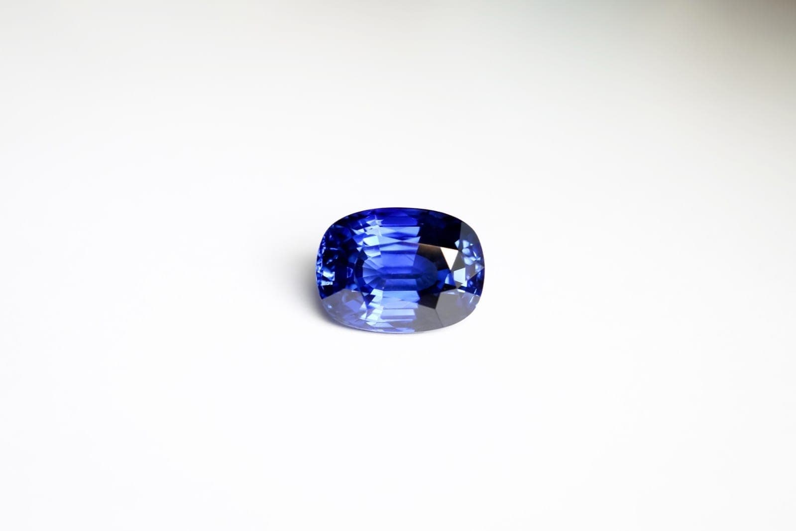 Ceylon sapphire before and after heat treatment side by side — showing silk dissolution and color refinement under controlled studio lighting