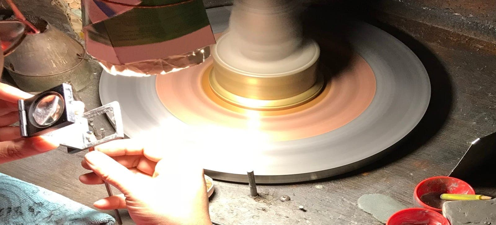 Digital caliper measuring a 6mm round sapphire at Lim Gems Factory Bangkok, showing 0.02mm precision reading against a specification sheet