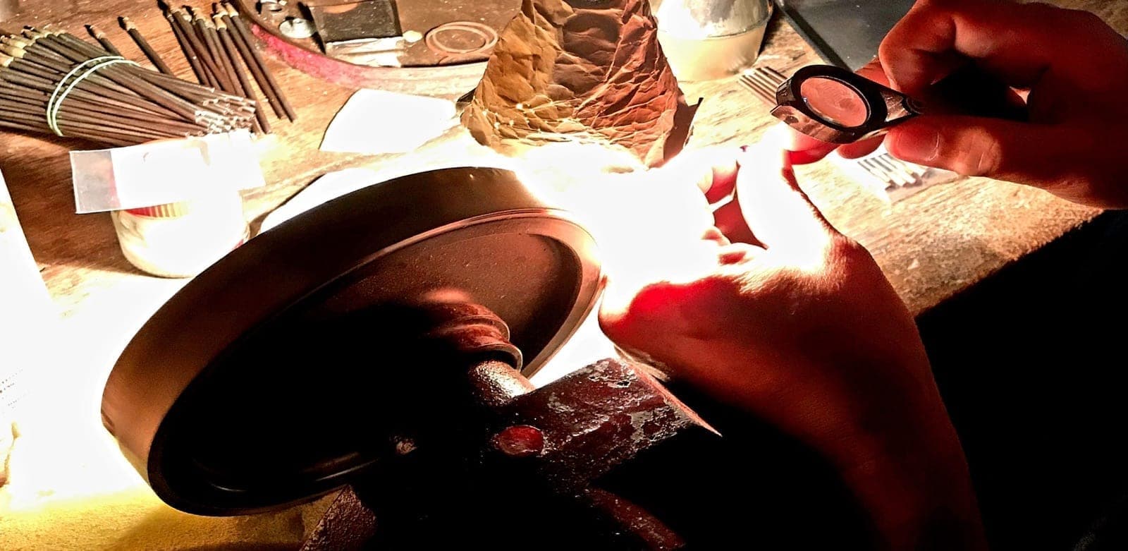 Master hand cutter at Lim Gems Factory Bangkok adjusting pavilion angle on a high-value ruby rough, with magnification loupe and faceting machine visible