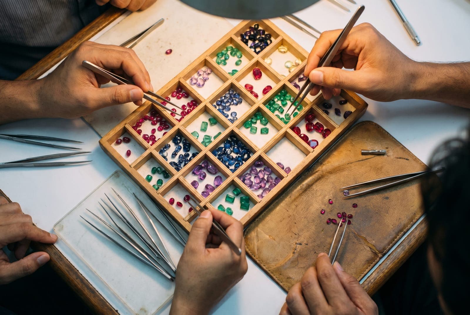 Overhead view of blue sapphires and rubies being sorted at Lim Gems Factory workspace in Bangkok